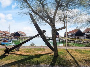 A waterfront property with a dock, boats, and a tree in the foreground. - 4 Person Holiday Home in Borre (Borre)