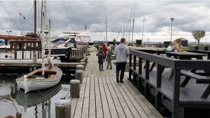 Une jetée en bois, avec des bateaux amarrés d’un côté et une table de pique-nique de l’autre.
