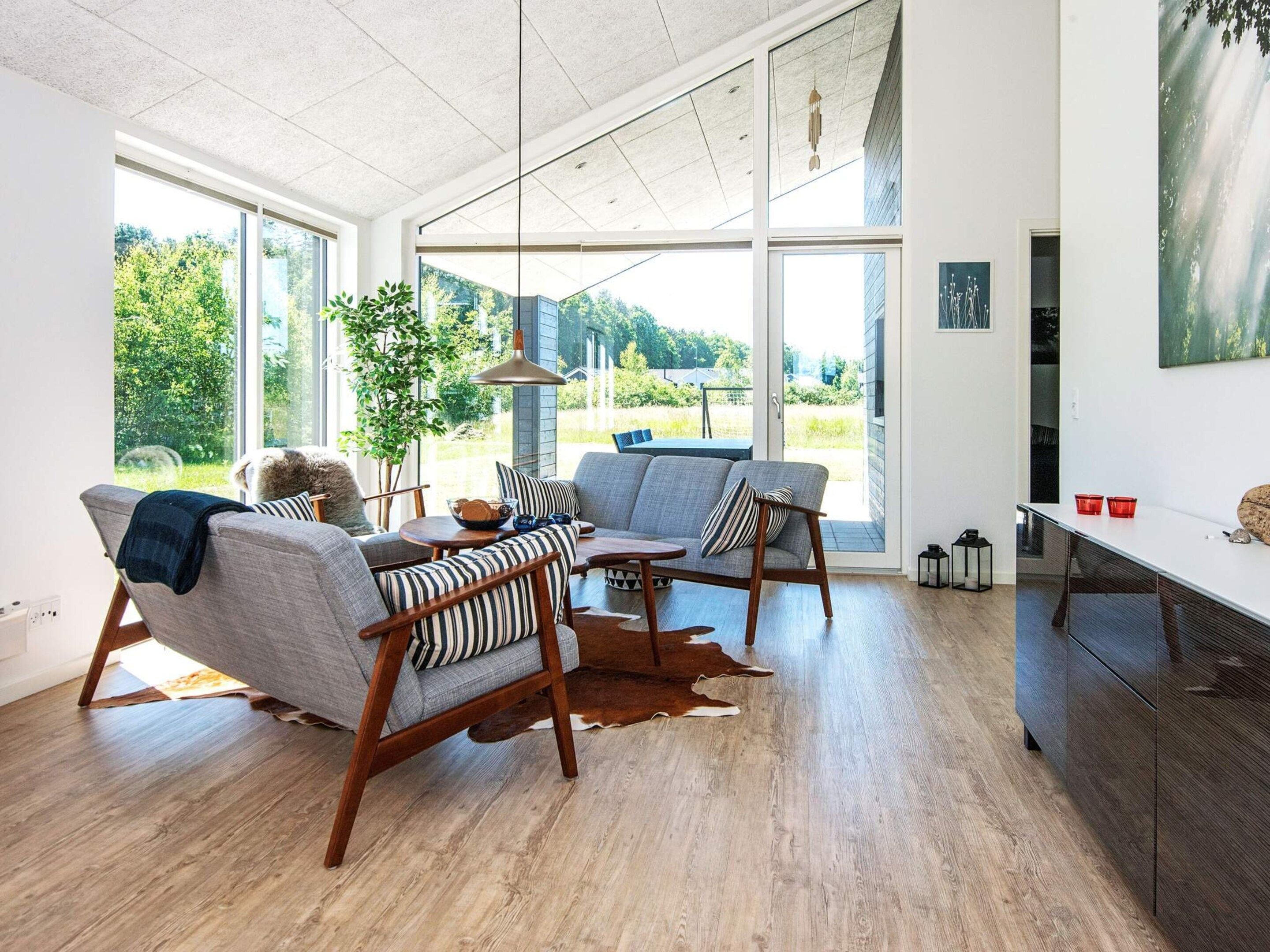 A modern living room with a large window, a dining area, and a view of the outdoors.
