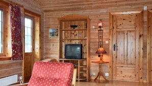 A wooden cabin interior with a television, a lamp, and a red upholstered chair. - 4 Person Holiday Home in Olden (Stryn)