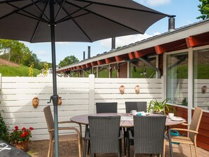 An outdoor patio with wicker furniture, a table, and an umbrella. - 4 Person Holiday Home in Aabenraa (Aabenraa)