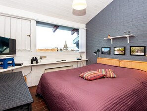 A bedroom with a bed, a television, a desk, and a window with a view. - 4 Person Holiday Home in Aabenraa (Aabenraa)