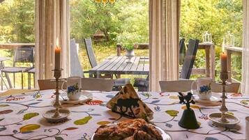 An outdoor dining area with a table set for two, featuring a floral tablecloth, candles, and a plate of food.