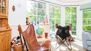A cozy room with a wooden cabinet, a brown leather chair, a wicker chair, and a globe on a small table. - Vibrant Holiday Home in Tarm near Sea (Hemmet)