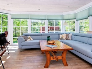 A room with a large window, a grey sofa, a wooden table, and a chair. - Vibrant Holiday Home in Tarm near Sea (Hemmet)