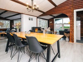 Un comedor con una mesa de madera, sillas negras y una araña.