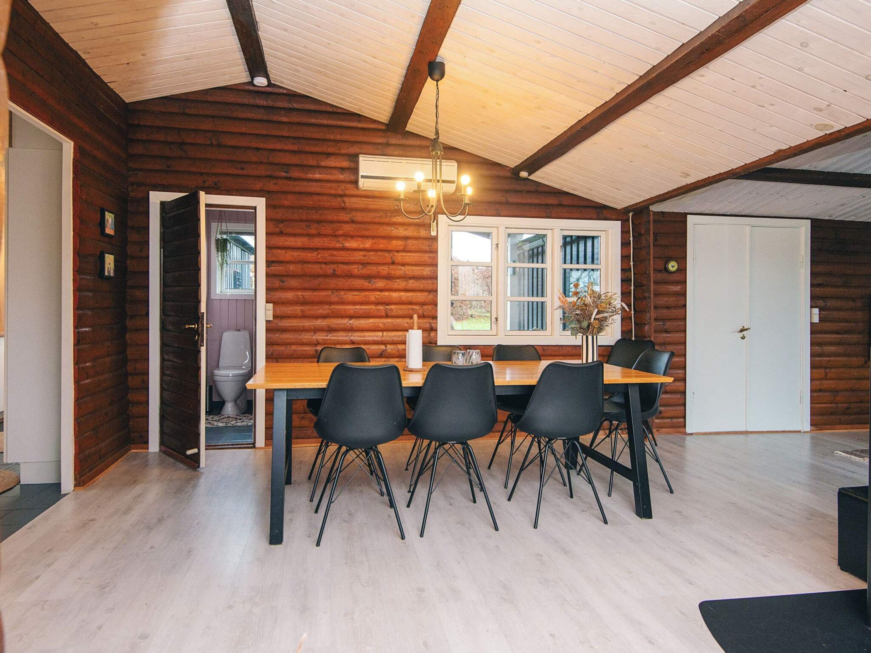 A dining area with a wooden table, black chairs, and a chandelier.
