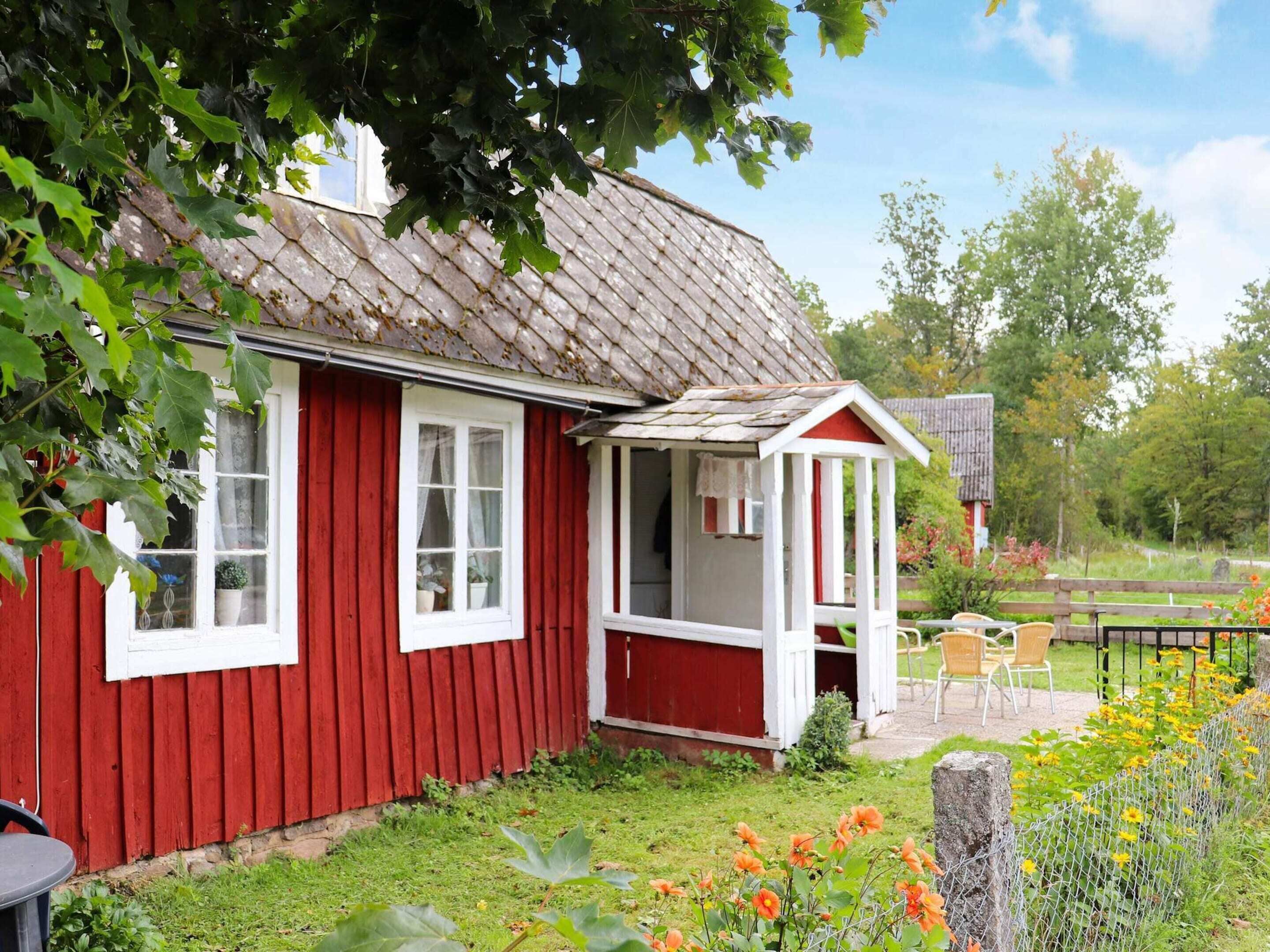 A red wooden house with a white window and a small porch.
