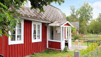 A red wooden house with a white window and a small porch.