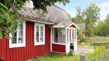A red wooden house with a white window and a small porch.