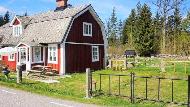 A red barn with a sloped roof, a small porch, and a picnic table. - 6 Person Holiday Home in Kyrkhult (Kyrkhult)