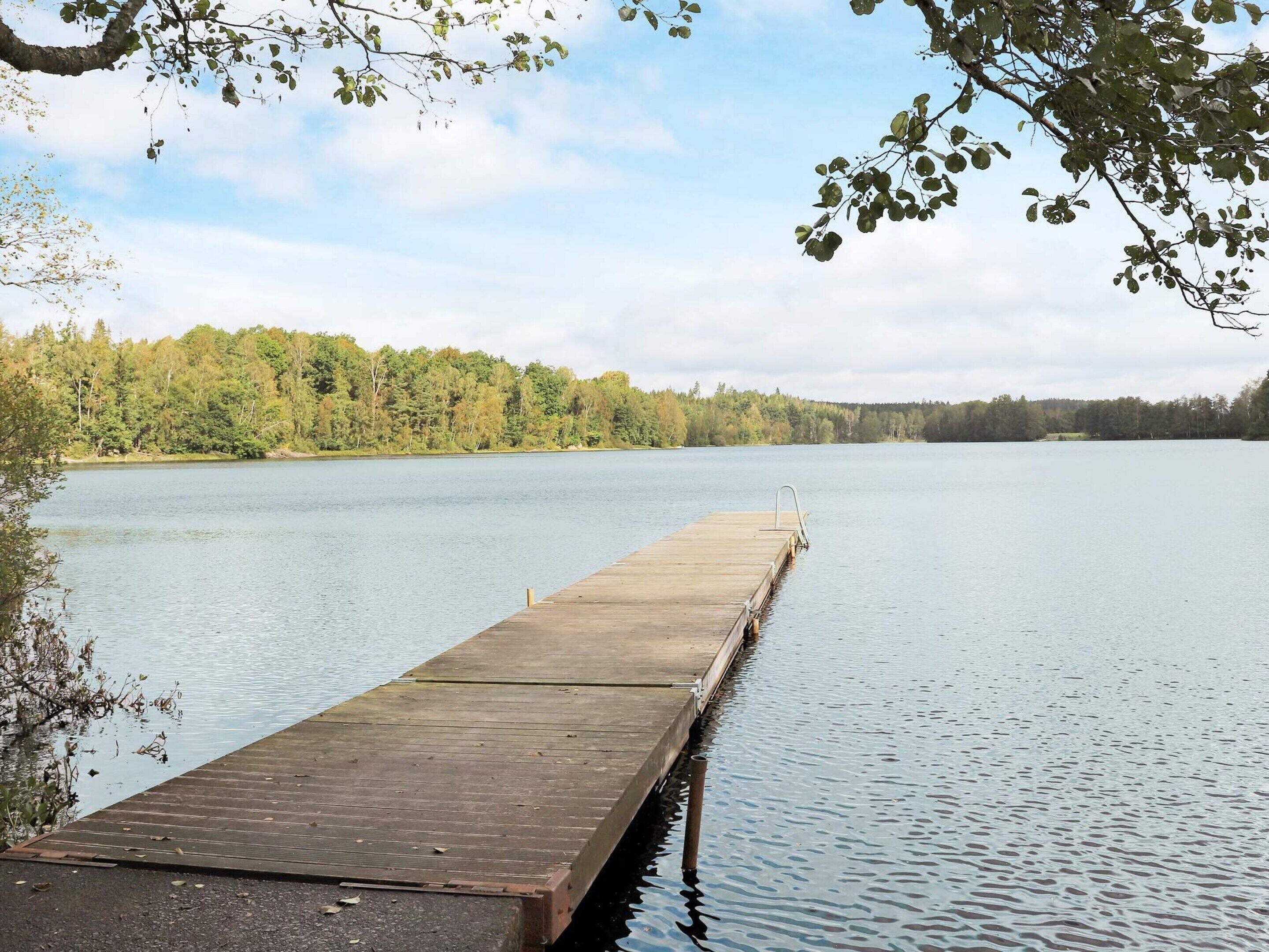 A wooden dock extending into a calm lake, surrounded by dense forest.