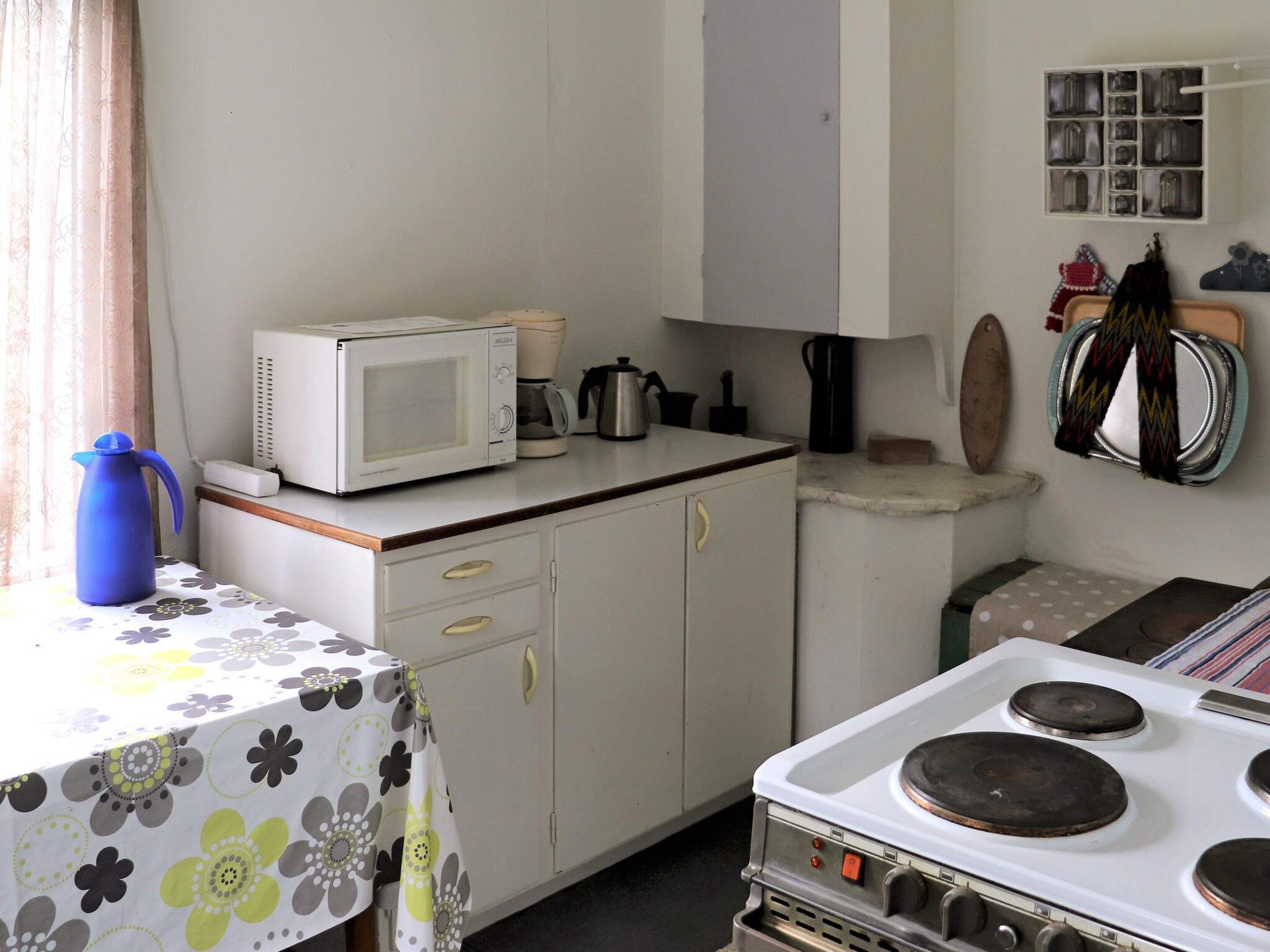 A compact kitchen with a microwave, coffee maker, and stove.