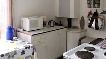 A compact kitchen with a microwave, coffee maker, and stove.
