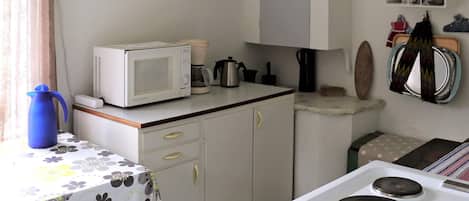 A compact kitchen with a microwave, coffee maker, and stove.