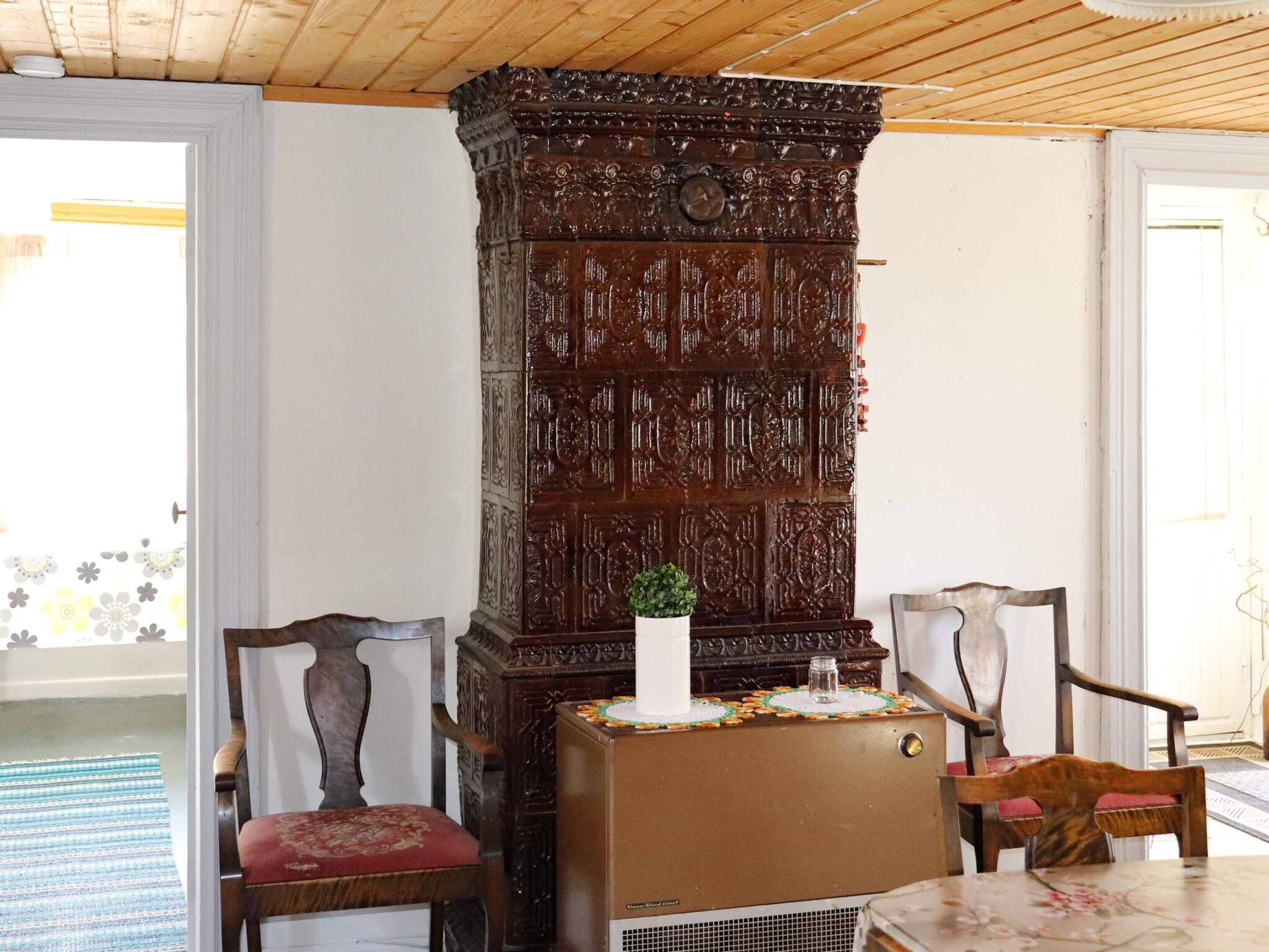 A room with a wooden cabinet, two chairs, a table, and a door.
