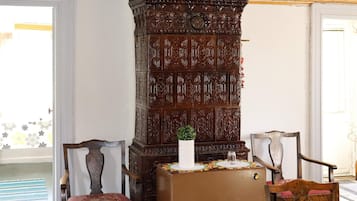 A room with a wooden cabinet, two chairs, a table, and a door.