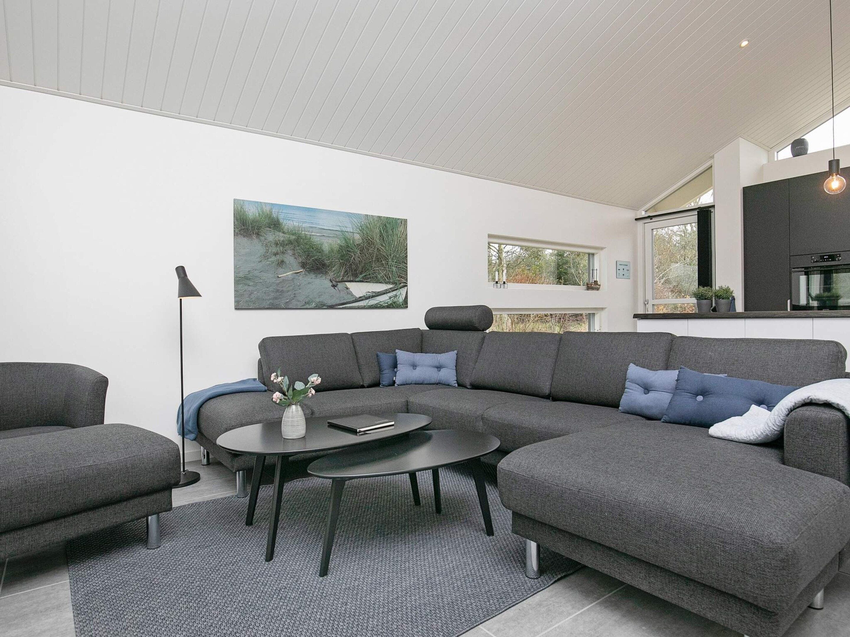 Una sala moderna con un sofá modular, una mesa de centro y una lámpara de pie.