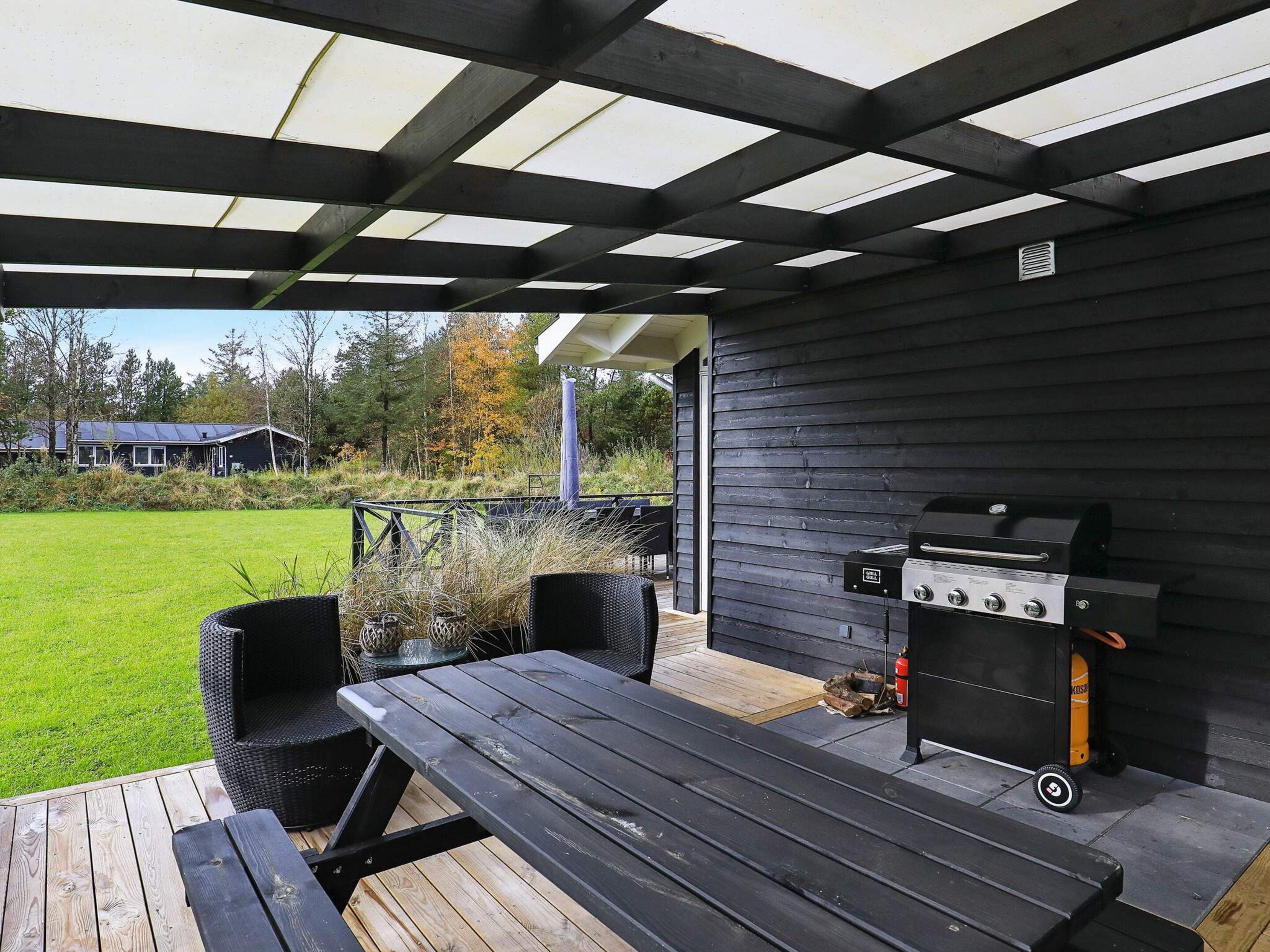 Eine Terrass mit Grill, Tisch und Stühlen.