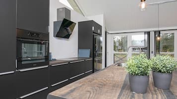 Cozinha moderna com armários escuros, forno embutido e bancada de madeira.