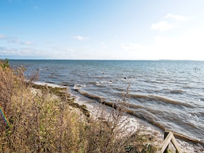 A coastal landscape with a sandy beach, rocky outcrops, and a wooden structure. - 8 Person Holiday Home in Hejls (Hejls)