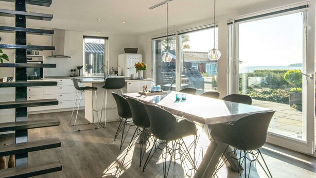 A modern kitchen with a dining area, large windows, and a view of the outdoors. - Seaside Serenity in Teglgarden-by Traum (Hejls)