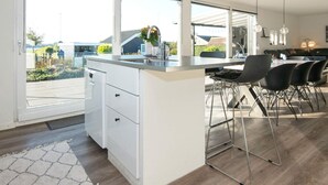 A modern kitchen with a large island, white cabinetry, and a view of the outdoors. - Seaside Serenity in Teglgarden-by Traum (Hejls)