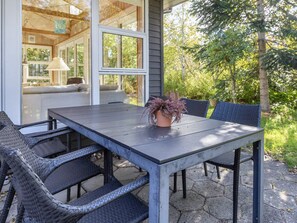 An outdoor patio with a table and chairs, a potted plant, and a view of a house and trees. - 8 Person Holiday Home in Thyholm (Thyholm)
