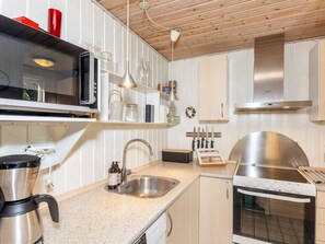A modern kitchen with white cabinetry, a stainless steel range hood, a built-in oven, and a coffee maker. - 8 Person Holiday Home in Thyholm (Thyholm)