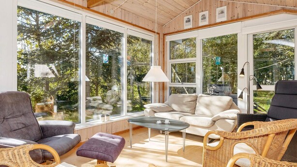 A cozy, well-lit room with large windows, a sofa, chairs, and a table. - 8 Person Holiday Home in Thyholm (Thyholm)