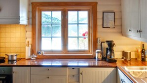 Eine Küche mit einem großen Fenster, Holzschränken, einer Kaffeemaschine und einer Arbeitsplatte mit verschiedenen Gegenständen.