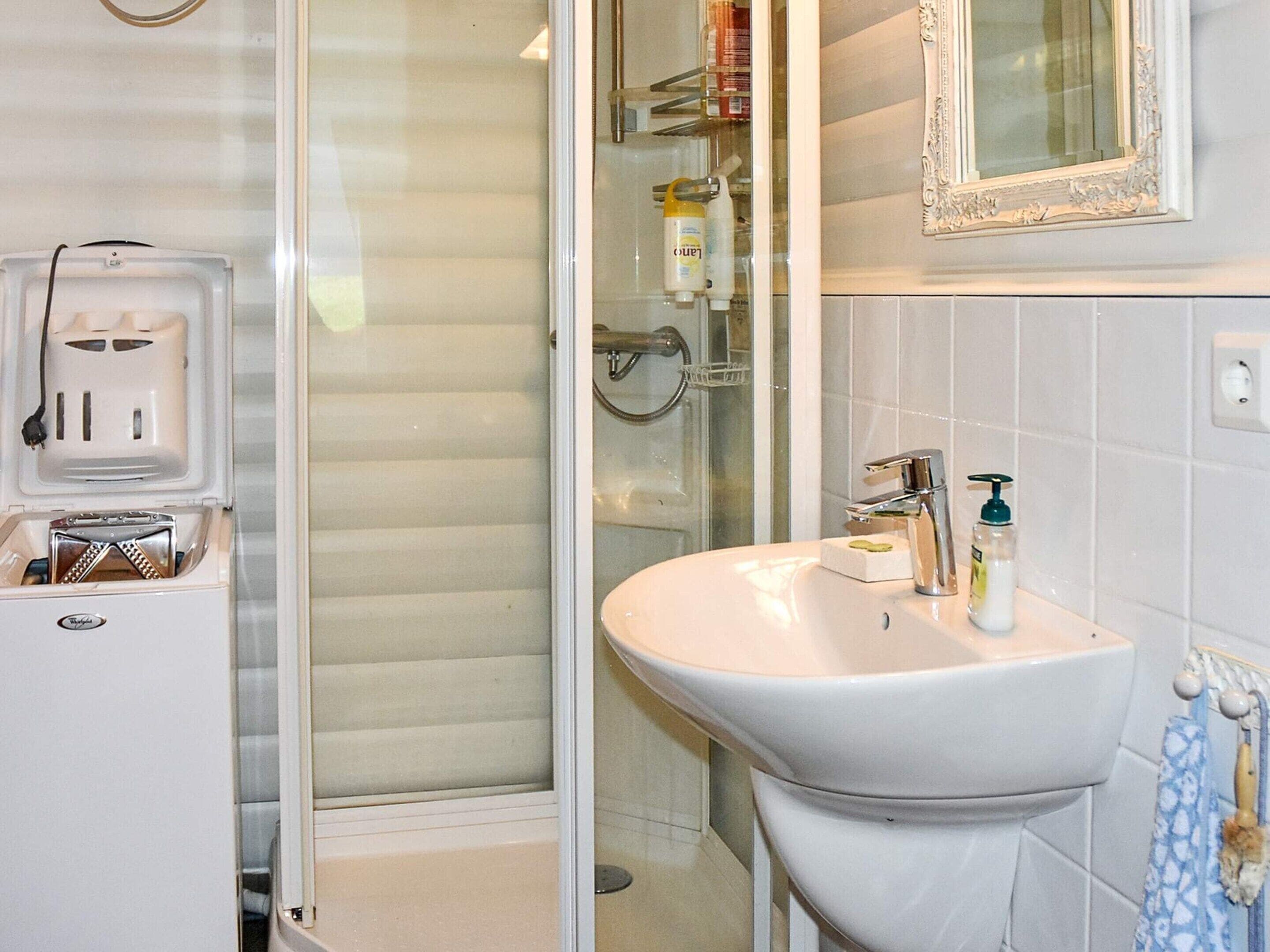 A bathroom with a white sink, a mirror, and a shower area.