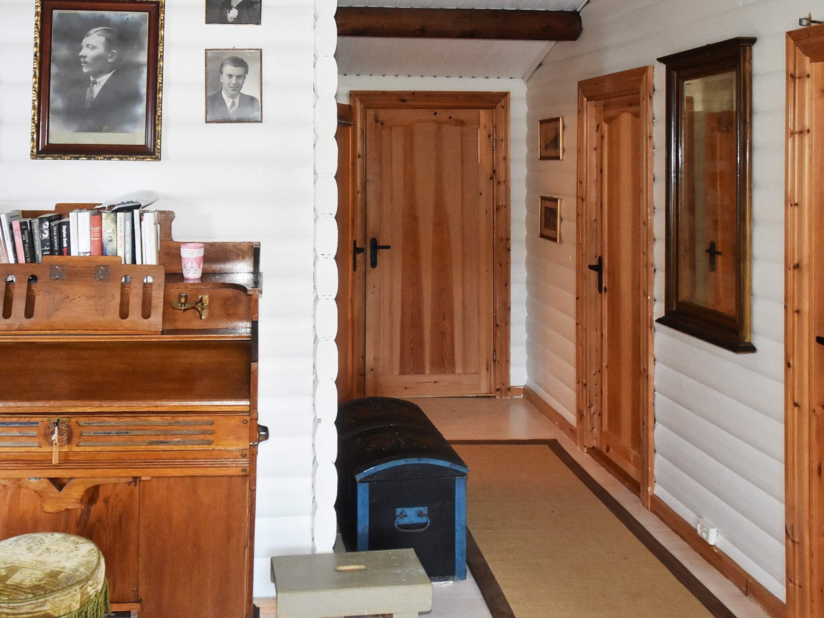 A hallway with wooden doors, a bench, and a wooden cabinet with books and a cup.