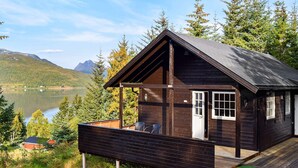 A wooden cabin with a deck, overlooking a lake and mountains. - 4 Person Holiday Home in Botnhamn (Senja)