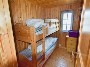 A wooden bunk bed room with a window and a small dresser.