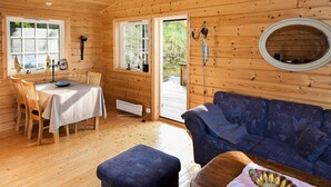 A wooden cabin interior with a dining area, a sofa, and a round mirror. - 4 Person Holiday Home in Botnhamn (Senja)
