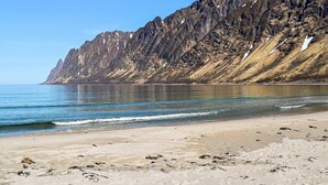 A beach with a rocky mountain backdrop. - 4 Person Holiday Home in Botnhamn (Senja)