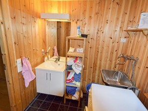 A compact wooden bathroom with a sink, mirror, and towel rack.