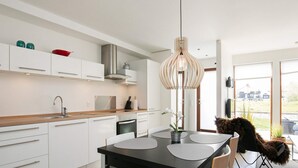 A modern kitchen with white cabinetry, a wooden countertop, and a black dining table.