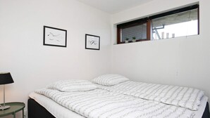 A bedroom with a bed, a nightstand, a lamp, and two framed pictures on the wall.