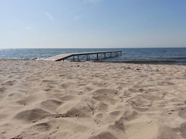 A sandy beach with a wooden pier extending into the water.