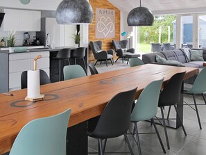 A modern kitchen with a wooden dining table, black chairs, and pendant lighting.