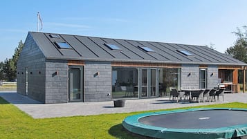 Un edificio moderno con techo inclinado, amplios ventanales y un área de estar al aire libre cubierta.