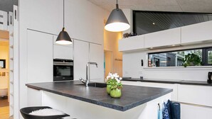 A modern kitchen with a central island, pendant lighting, and a view of the outside. - 5 Star Holiday Home in Hjorring (Hjørring)