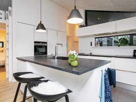 Una cocina moderna con una isla central, iluminación colgante y vistas al exterior.