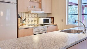 A kitchen with a refrigerator, microwave, stove, and sink. - 6 Person Holiday Home in Aakirkeby (Akirkeby)