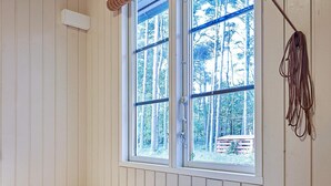 A bedroom with a large window, wooden walls, a bed, and a hanging cable. - 6 Person Holiday Home in Aakirkeby (Akirkeby)