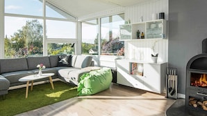 En moderne stue med en grå sofa, en grøn puf og en pejs.