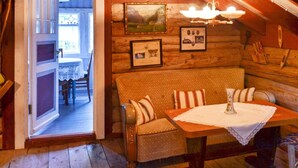 A cozy log cabin interior with a wooden bench, a table with a white tablecloth, and framed pictures on the wall. - 3 Person Holiday Home in Bofjorden (Surnadal)