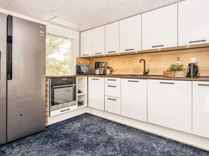 A modern kitchen with white cabinets, stainless steel appliances, and a wooden countertop. - 8 Person Holiday Home in Hvide Sande (Hvide Sande)